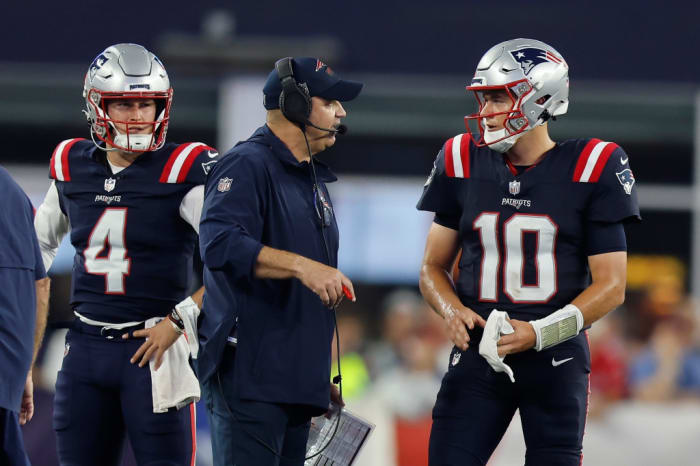 New England Patriots offensive coordinator Bill O’Brien speaks with quarterback Mac Jones (10) as quarterback Bailey Zappe (4) looks on.